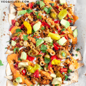 Healthy Vegan Loaded Nachos with Homemade Lime Tortilla Chips, Black Beans, Tofu Taco Crumble, Onion, Tomato, Jalapeno, Nacho Cheese Sauce, Cilantro, Avocado, and Pepperoncini. Oil Free and Gluten Free - by Veggie Lexi
