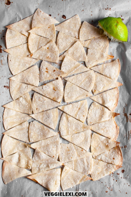 Oil free tortilla chips with lime juice and salt on a baking sheet.